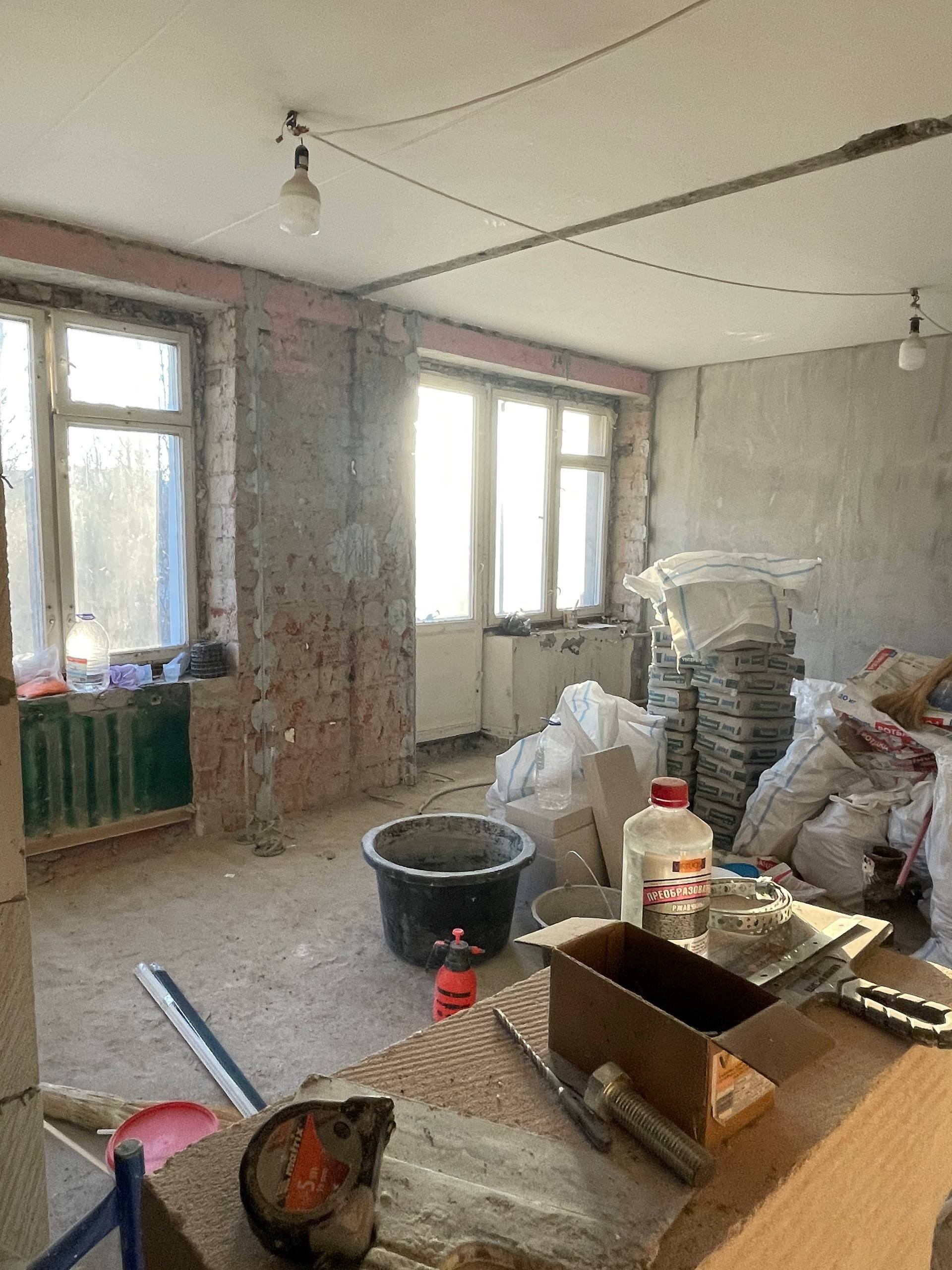 Комната во время ремонта с окнами, материалами и инструментом
